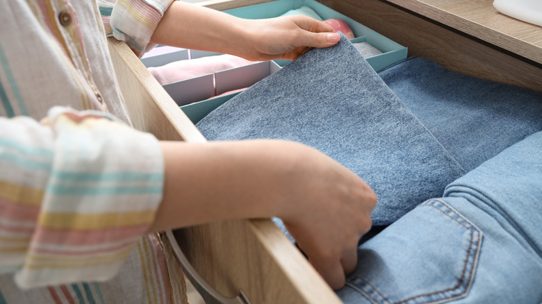 Hands folding jeans in drawer