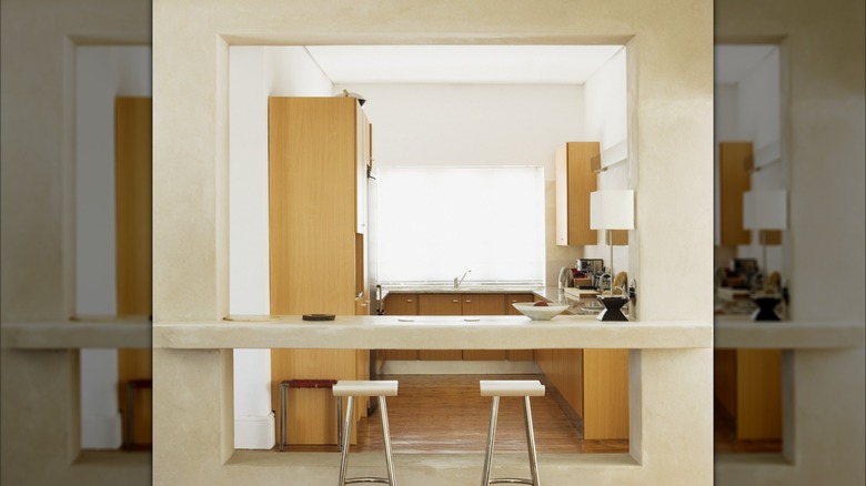 A modern kitchen pass-through window that extends nearly floor to ceiling and features a floating countertop