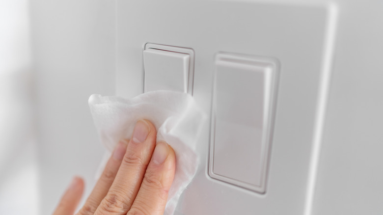 Hand wiping a light switch with a cloth