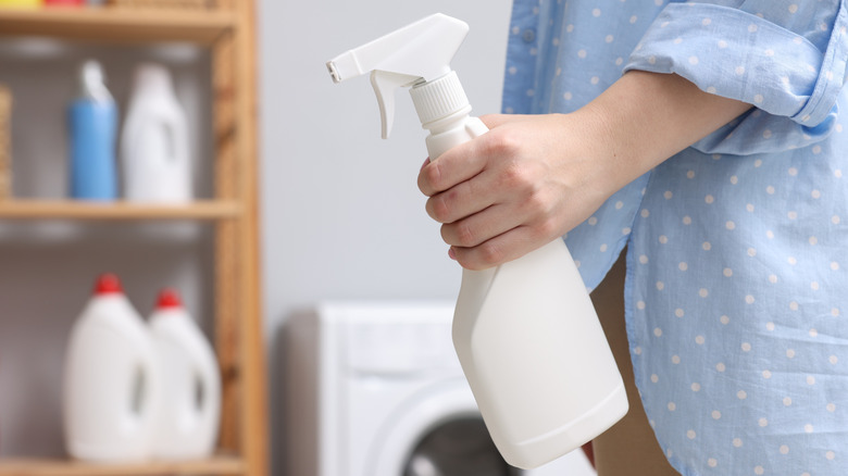 Woman holding spray bottle in laundry room