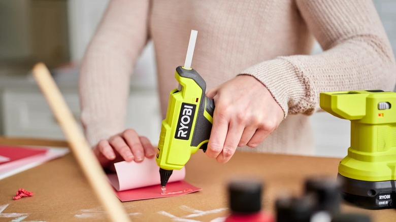 Woman using Ryobi One+ 18V Cordless Compact Glue Gun on paper project