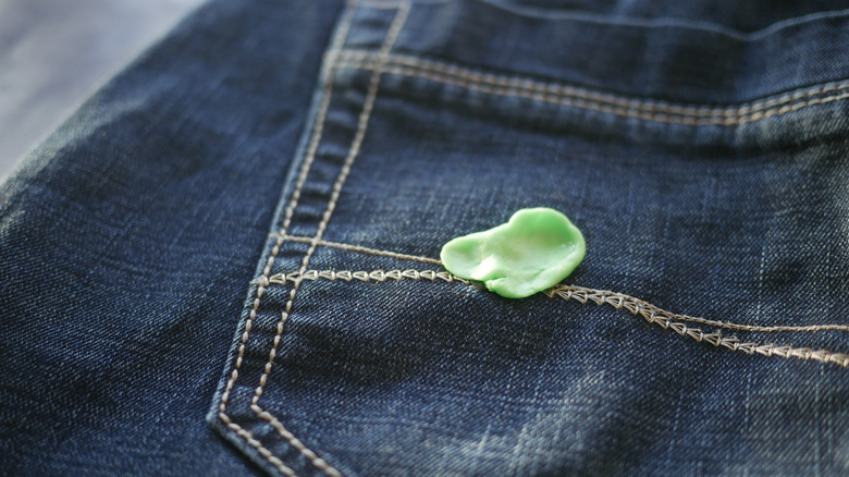 Green chewing gum stuck to blue denim pocket