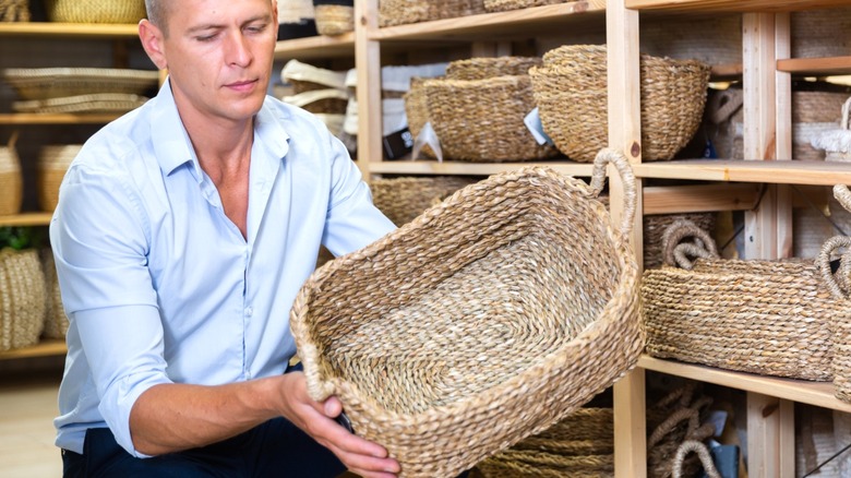 man looking at wicker basket at thrift store