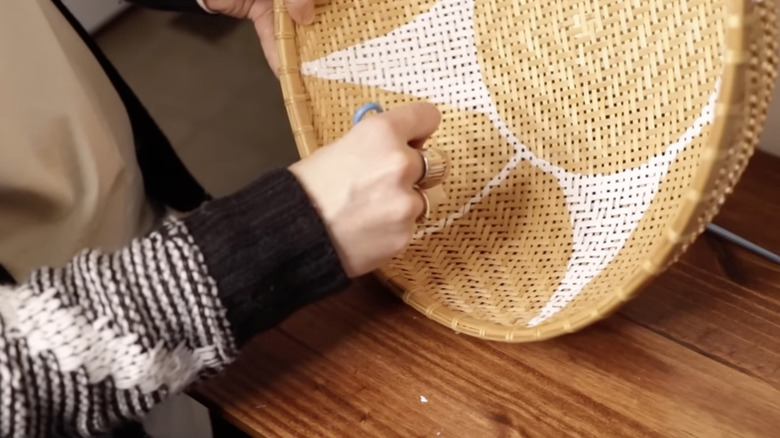 Person hand painting a woven basket