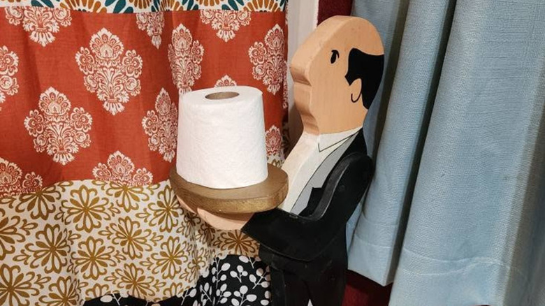 Vintage butler statue holding a tray with a toilet paper roll on top