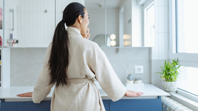 A woman smiles in a robe in the bathroom