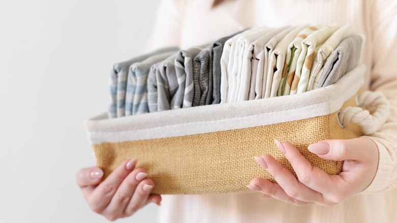 A woman holds a basket full of folded small fabrics