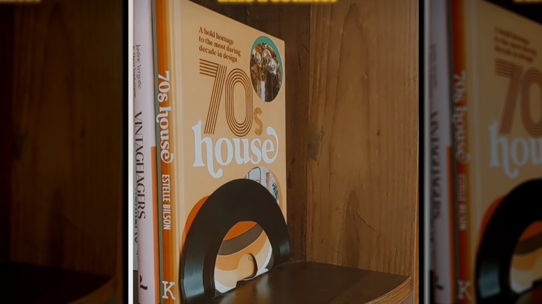Books on a timber bookshelf with a bent vinyl record used as the bookend