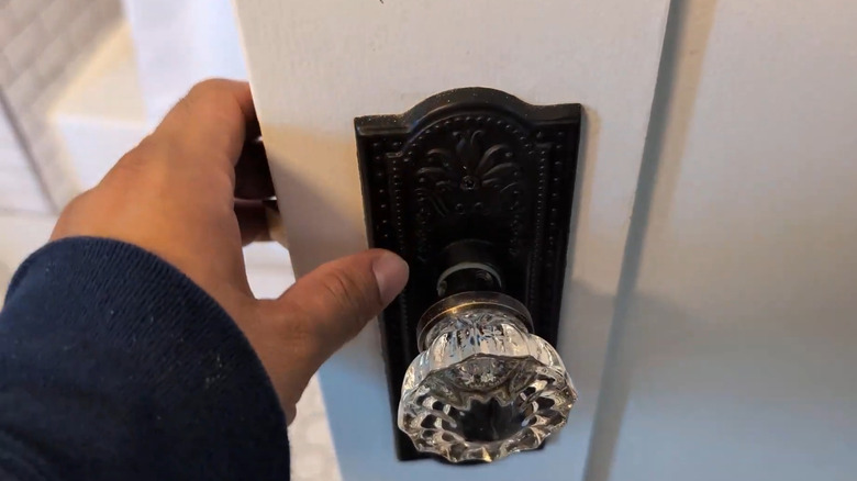 Person reaching for a door with a glass door knob
