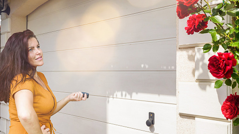 A woman stands in front of closed white garage doors