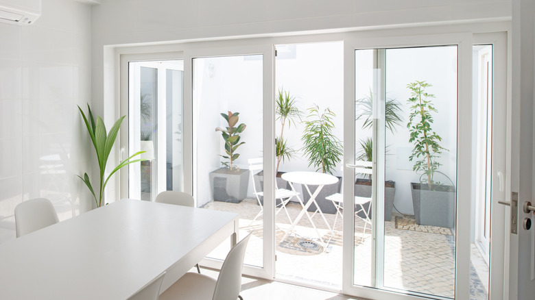 Sliding glass door in white room opening to patio with plants