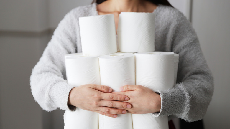 A person holding stacks of toilet paper