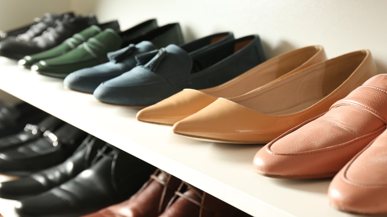 Pairs of shoes on white shelf.