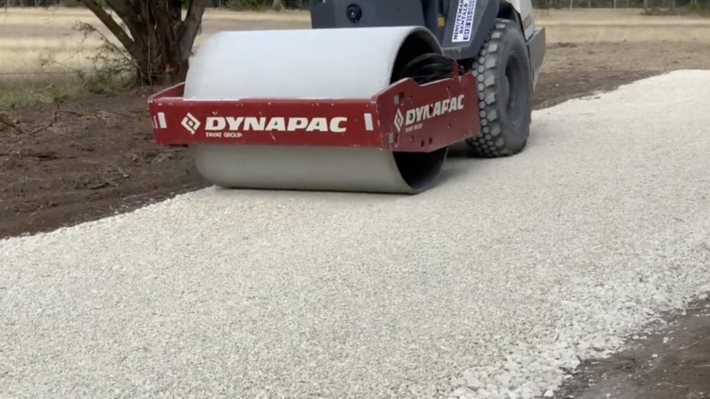 Roller compacting a gravel driveway.