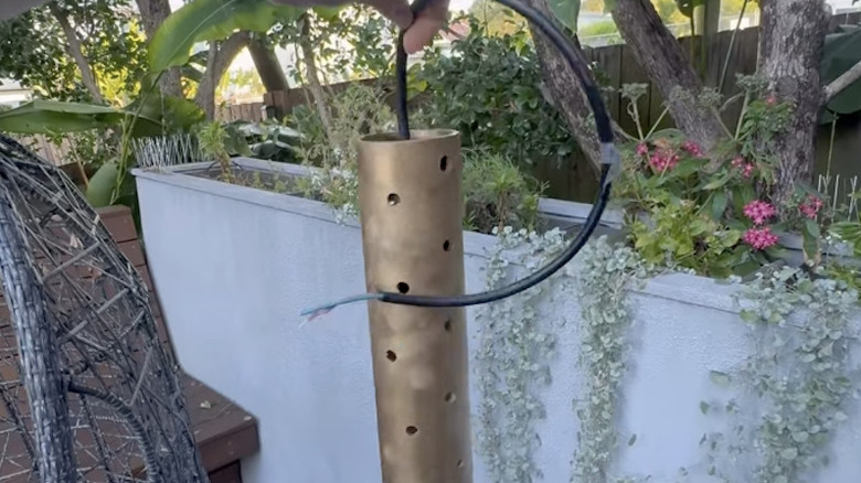 A DIY outdoor hanging light made out of PVC pipe painted gold