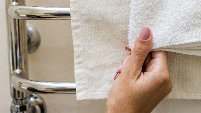 Woman's hand reaching for towel hanging from a chrome rack