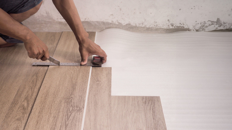 a technician is installing luxury plank vinyl flooring.