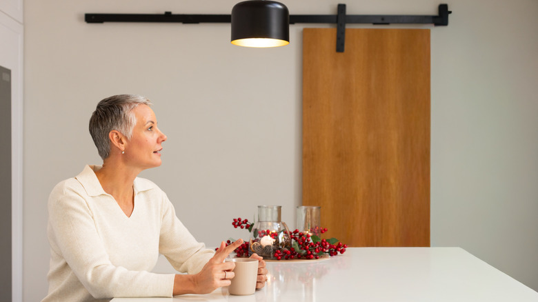 A woman seated at a table with a sliding barn door in the background.