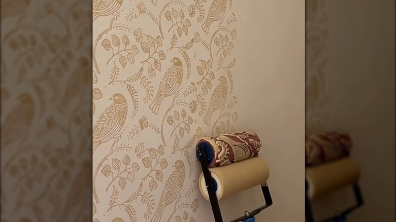 Creator using a stamp roller to create a bird and floral wallpaper-like design