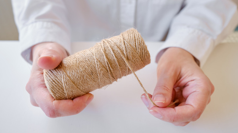 Hands holding a roll of jute twine