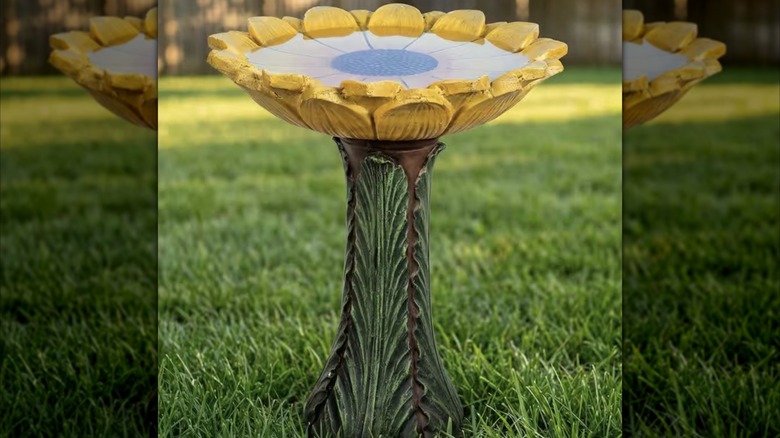 A sunflower shaped and colored concrete birdbath