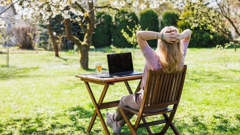 Woman relaxing in yard with laptop admiring the view
