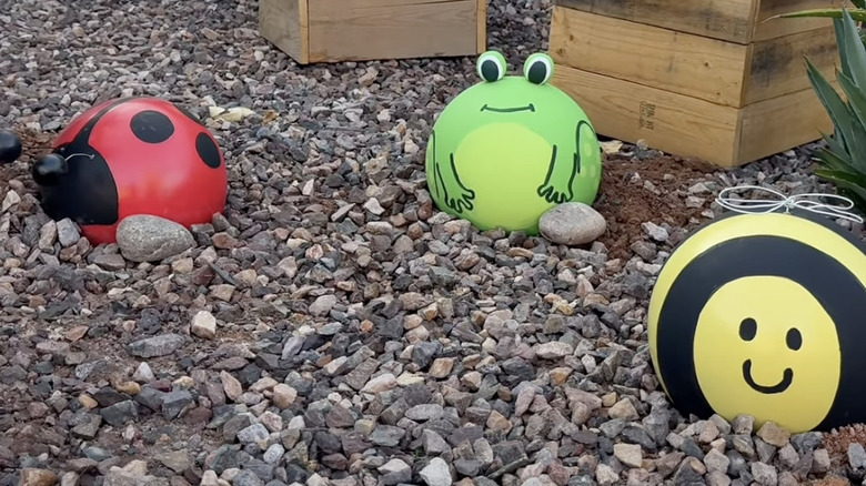 bowling ball garden critters decorations in a gravel garden area