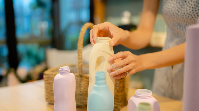 Woman picking up an empty detergent bottle