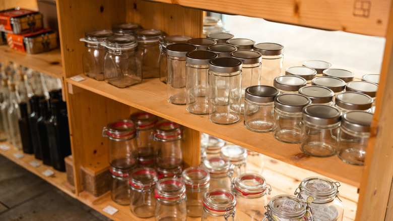 Wooden shelf full of assorted glass mason jars