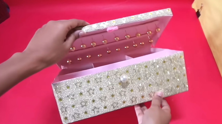 A unique DIY jewelry box made from a shoebox is opened to show punk lining and push pins