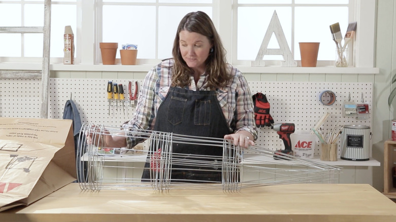 A woman looks at a stack of tomato cages on a table in a craft studio
