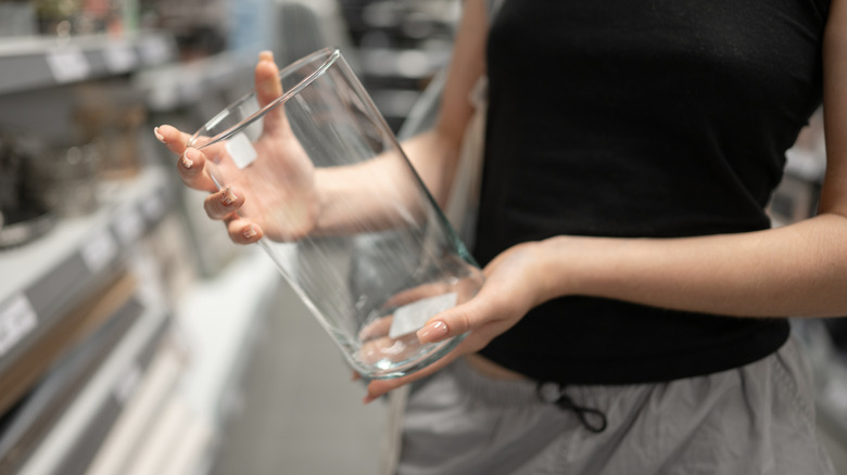 Person holding a clear glass vase in the aisle of a store