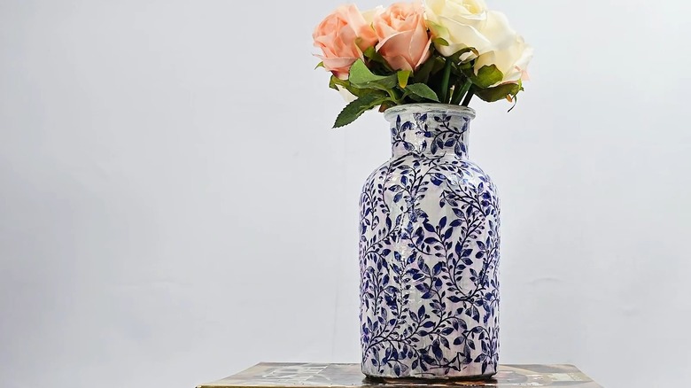 A chinoiserie-style vase with imitation flowers placed over a stack of books