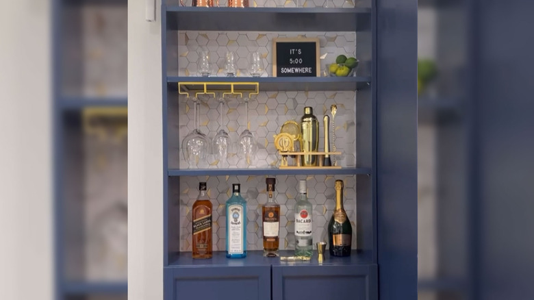 Blue bar shelf with glasses, barware, and bottles