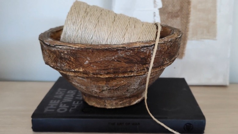 A paper-mache bowl with a spool inside