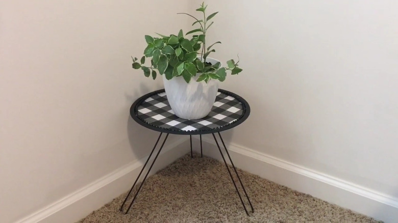 A black farmhouse DIY plant stand with checkered fabric and a small plant on top