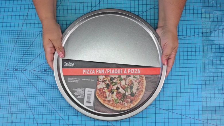 A woman's hands holding a Dollar Tree pizza pan