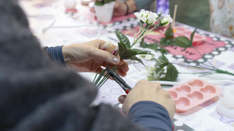 hands cutting fake plant stem