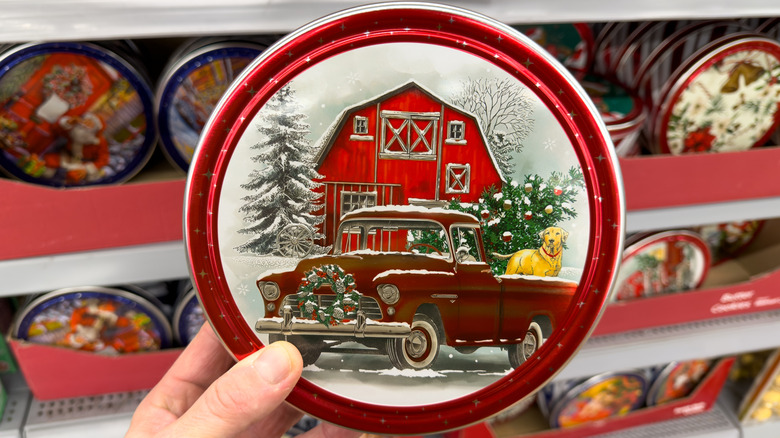 A shopper's hand holding a cookie tin up at the store