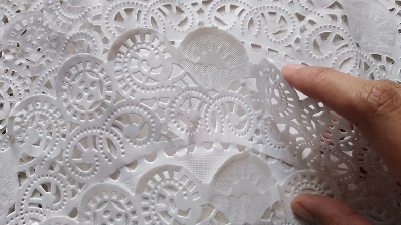A person flipping through a stack of paper doilies.