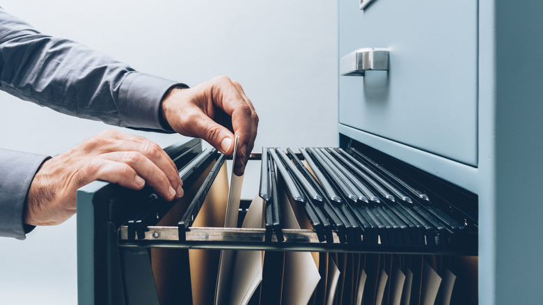 A man opening a filing cabinet.