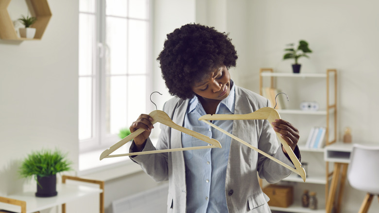Woman holding up two wooden hangers