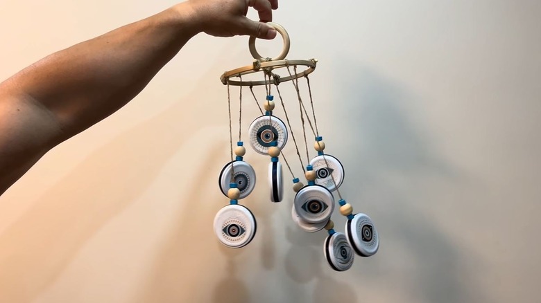 Woman holding finished DIY windchime made from old jar lids