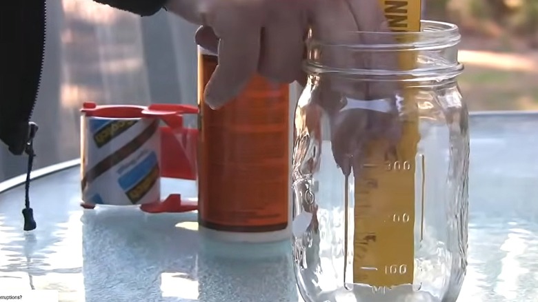 Woman sticking a ruler in a glass jar