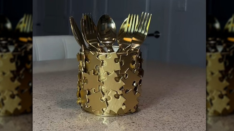 A gold utensil holder on a kitchen countertop