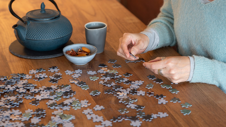 Woman is looking at puzzle pieces spread out on a table