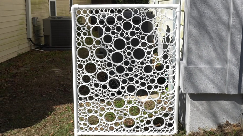 Small privacy screen made from sections of PVC pipe installed by the side of a house