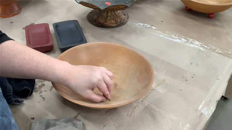 Person removing the price tag from a thrifted wooden bowl