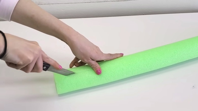 woman cutting open a foam pool noodle