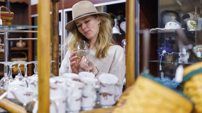 Woman at a thrift store holding and inspecting a glass